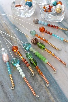 several beads and bead necklaces on a marble counter top with two glass bowls in the background