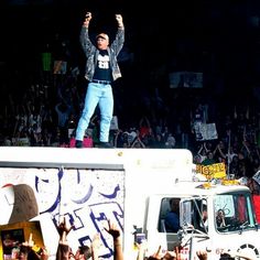 a man standing on top of a truck in front of a crowd