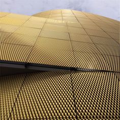 the side of a building that is made out of gold colored metal mesh and has a clock on it