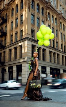 a woman is walking down the street with yellow balloons in her hand and a bag on her head