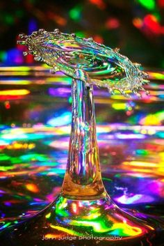 a close up of a glass vase with water in it and colorful lights behind it