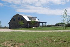 a large barn sits in the middle of a grassy field