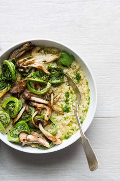 two bowls filled with rice, broccoli and mushrooms next to silver spoons