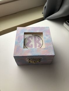 a small wooden box sitting on top of a white table next to a phone and window