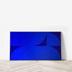 an abstract blue painting on the wall next to a wooden floor with white walls and parquet floors