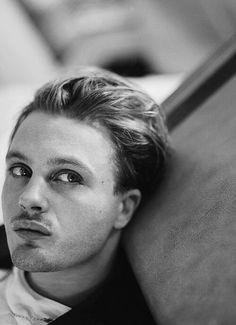 black and white photograph of a man leaning against a wall