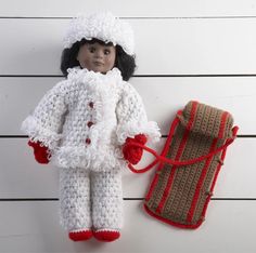 a crocheted doll next to a bag and purse on a white wooden surface