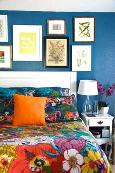 a bed with colorful bedspread and pictures on the wall above it in a bedroom