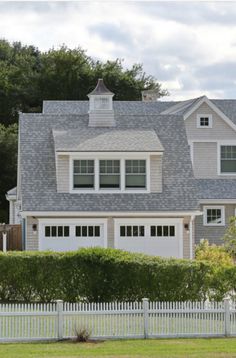 a large house with two garages and a white picket fence