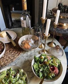 a marble table topped with plates and bowls filled with food next to wine glasses on top of it