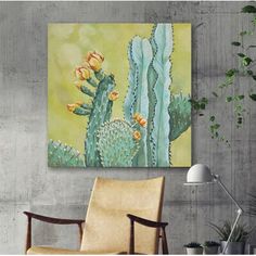 a cactus painting hanging on a wall next to a chair