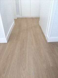 an empty room with white walls and wood floors is seen in this image from the front door