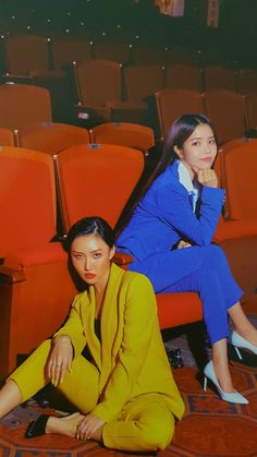 two women sitting on the floor in front of an empty theater auditorium with red seats