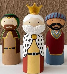 three wooden toy figurines with crowns on them