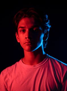 a young man in a red shirt is looking at the camera with an intense look on his face