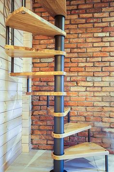 a spiral wooden shelf in front of a brick wall