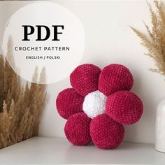 a crochet flower sitting on top of a shelf next to some dried grass