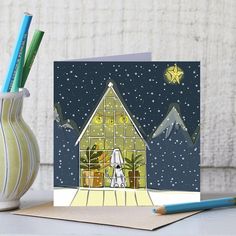 a christmas card with a nativity scene in front of a lit up house on a snowy night