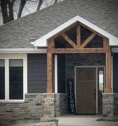 a welcome sign is in front of a house with stone pillars and an entry way