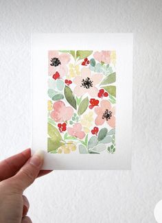 a person holding up a card with flowers on it in front of a white wall