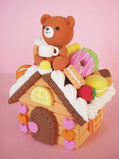 a teddy bear sitting on top of a toy house filled with donuts and doughnuts