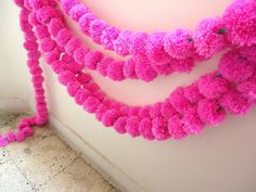 pink pom - poms hanging from the side of a wall