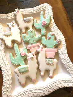 decorated cookies in the shape of llamas and cacti on a plate