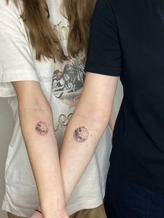 two people holding hands with tattoos on their arms