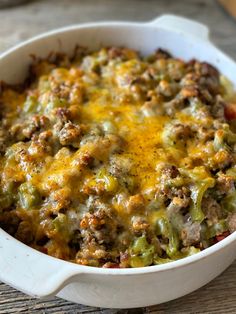 a casserole dish with meat, cheese and vegetables in it on a wooden table