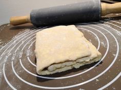 an uncooked pizza dough sitting on top of a cookie sheet next to a rolling pin