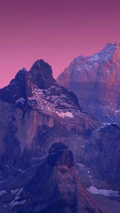 the mountains are covered in snow at sunset