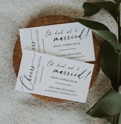 two wedding cards sitting on top of a wooden plate next to a potted plant