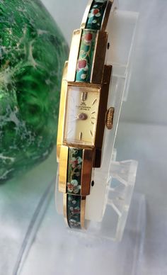 This is a very special and quite unique and beautiful gold plated floral enameled Bucherer 1960's ladies bangle bracelet watch. It is a mechanical, manual winding watch and has 17 jewels and made in Switzerland. Spring loaded adjustable cuff band, cream color dial with gold plated hands and markers. This very beautiful watch was just fully serviced and is running beautifully! This will make a wonderful addition to any jewelry collection! What a treasure!  Excellent and unforgettable gift idea! I ship promptly and pack with great care, I am happy to answer any questions you may have. Thank you for viewing this listing, Lynn Bucherer Jewelry, Funky Watches, Ladies Bangles, Beautiful Watch, Cuff Watch, Watch Women, Watch Bracelet, Beautiful Watches, Watch It