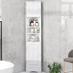 a bathroom with a white cabinet next to a bathtub and a plant in the corner