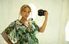 a woman taking a selfie in front of a mirror wearing a dress and holding a camera