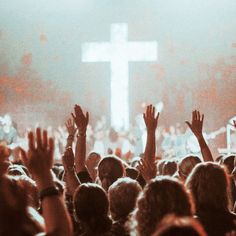 a group of people raising their hands in front of a cross