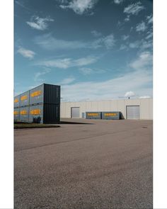 an empty parking lot with several storage units on the side and one large building behind it