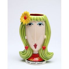 a ceramic vase with a woman's face painted on the side and flowers in her hair