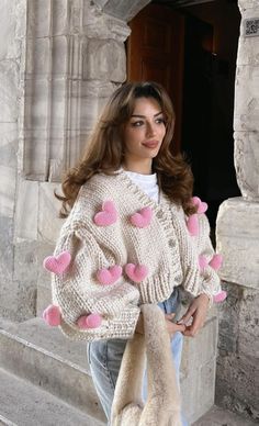 a woman is standing on the steps wearing a sweater with hearts