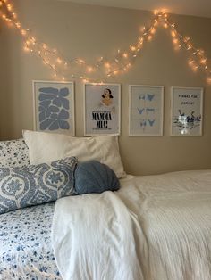 a bedroom with lights strung above the bed and pictures on the wall over the headboard