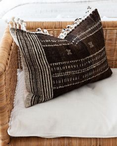 a wicker chair with two pillows on it and a white pillow in the back