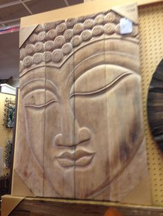 a wooden carving of a buddha face on display in a shop with other wood carvings