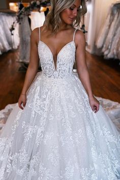 a woman in a white wedding dress standing on a bed with her hands behind her back