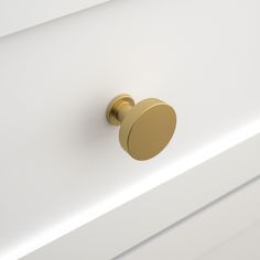 a close up of a white cabinet with a gold knob on the front and bottom