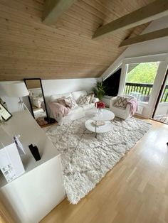 a living room filled with furniture and a large white rug on top of a hard wood floor