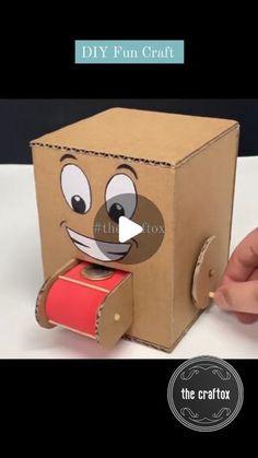 a cardboard box with a face on it and a roll of red tape in front of it