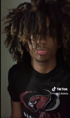 a man with dreadlocks standing in front of a wall