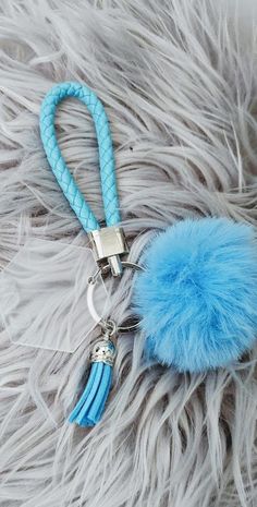 a fluffy blue pom - pom keychain with a metal clip