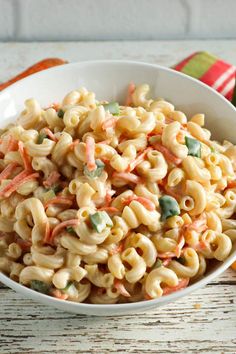 a white bowl filled with macaroni salad on top of a wooden table