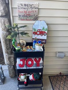 a cart filled with christmas items sitting on top of a porch next to a house